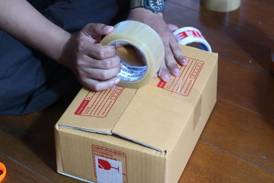 High angle view of man packing box on table