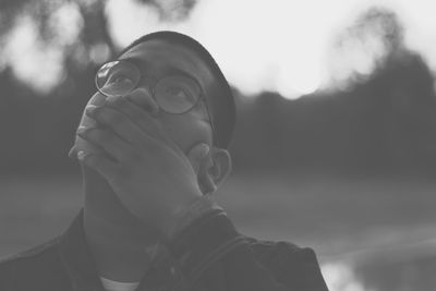 Close-up of thoughtful young man covering mouth while standing outdoors