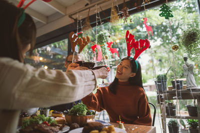 Female friends toasting wineglasses while sitting at table in restaurant