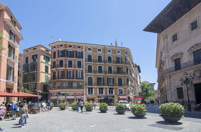 People on street amidst buildings in city against sky