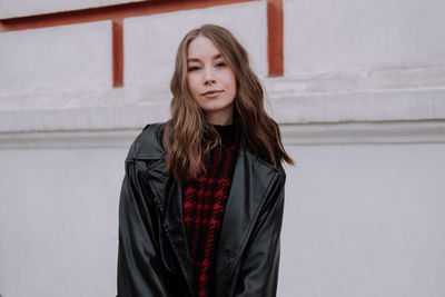 Portrait of beautiful young woman standing against wall