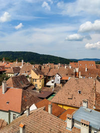 Tiled roofs of ancient european greentown on background of cloudy sky. sighisoara, romania.