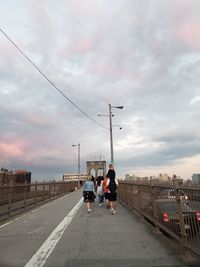 People on road in city against sky during sunset