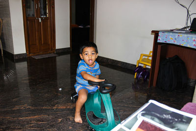 Portrait of boy sitting on toy at home