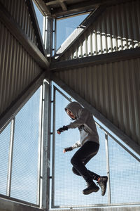 Low angle view of man jumping against building