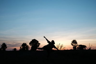 Silhouette people on field against sky during sunset