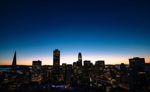 Modern buildings against clear blue sky at sunset