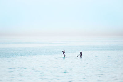 People on sea against clear sky