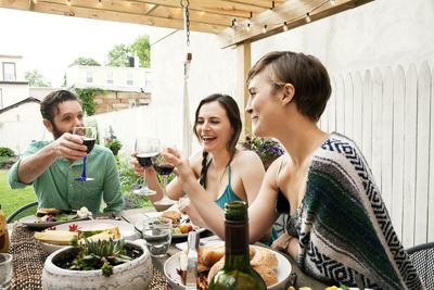 Friends toasting wineglasses while sitting at table in yard