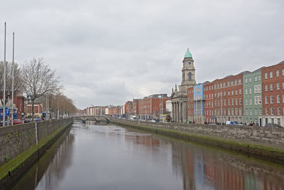 Canal amidst buildings against sky in city