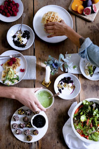 Cropped hands of couple having food at table while sitting by wall