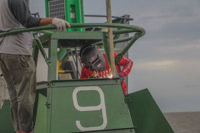 Worker welding on boat deck in sea