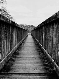 Boardwalk amidst trees against sky