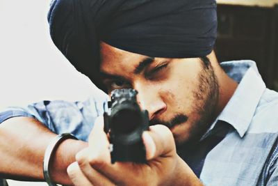 Close-up portrait of young man holding camera