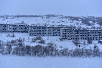 Buildings on snow covered field against sky