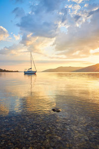 Sailboat in sea against sky during sunset