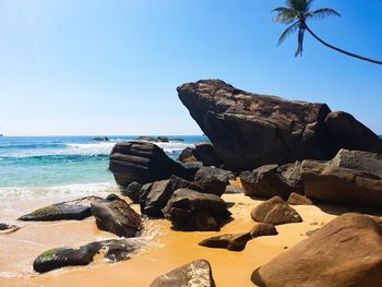 Rocks on beach against clear blue sky