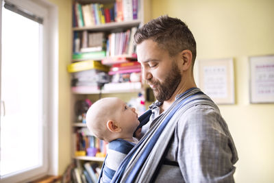 Father with baby son in sling at home