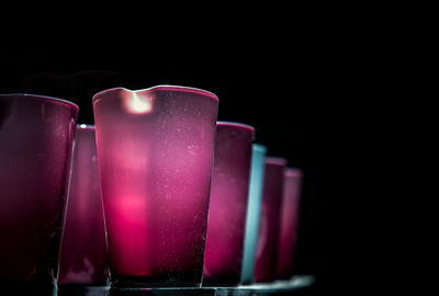 Close-up of pink candle on table against black background