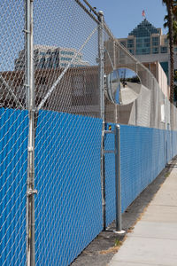 Chainlink fence by footpath against building