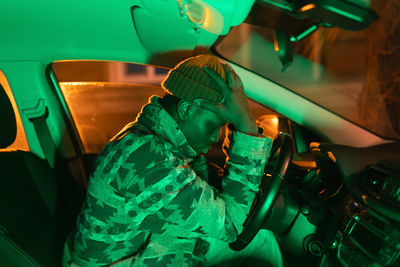 Depressed african man in car thinking about money problems, black upset guy in auto at night time