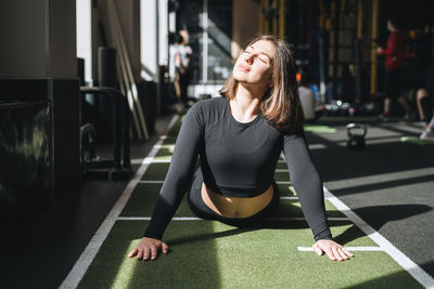 Young brunette woman doing stretching pilates, practice yoga on mat in fitness club