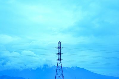 Low angle view of electricity pylon against blue sky