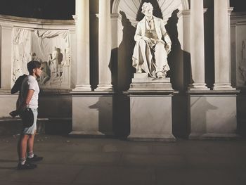 Low section of woman standing by statue