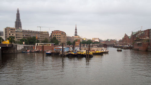 Boats in river against buildings in city