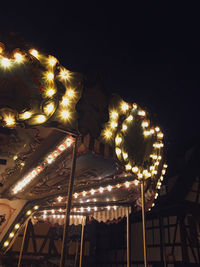 Low angle view of illuminated carousel against sky at night