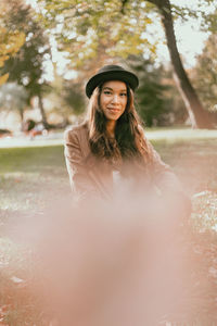 Portrait of smiling young woman standing against plants