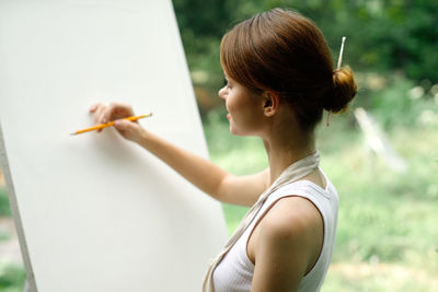 Side view of young woman writing in book