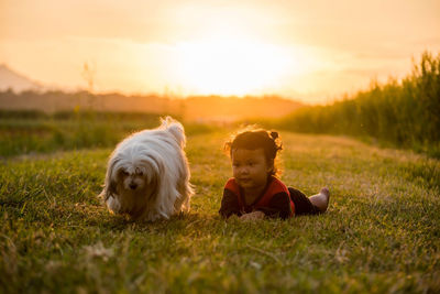 Cute girl lying by dog on grass