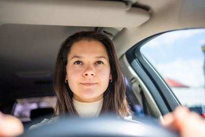 Portrait of young woman sitting in car