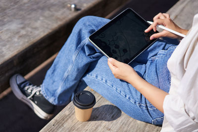 Midsection of woman using digital tablet