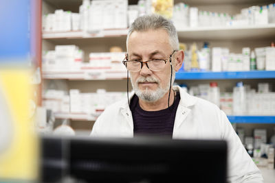 Pharmacist wearing eyeglasses using computer in pharmacy