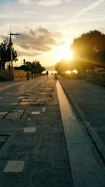Road by street against sky during sunset