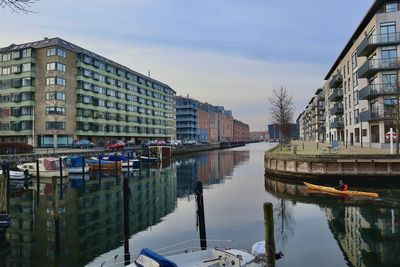 Canal amidst buildings in city against sky