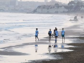 Rear view of people walking on beach