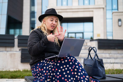 Young woman using smart phone while sitting on camera