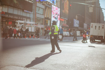 Full length of man working on city street against buildings during sunny day