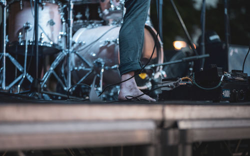 Low section of man standing on metal structure by musical instruments