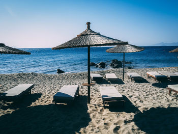 Lounge chairs by swimming pool at beach against clear sky