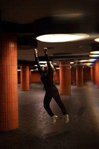 Full length of woman dancing at illuminated shop