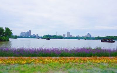 Scenic view of river by cityscape against sky