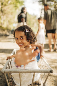 Portrait of happy girl waving while sitting in toy wagon