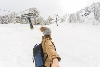 Rear view of man skiing on snow covered field