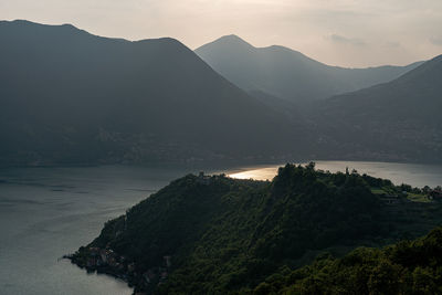 Scenic view of sea and mountains against sky during sunset