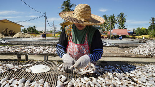 Woman selling fishes at market against sky