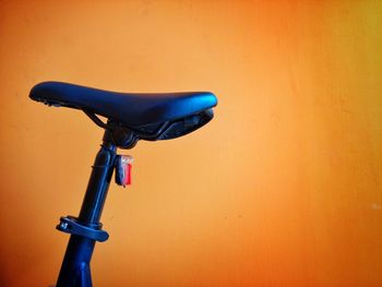 Close-up of bicycle seat against orange wall